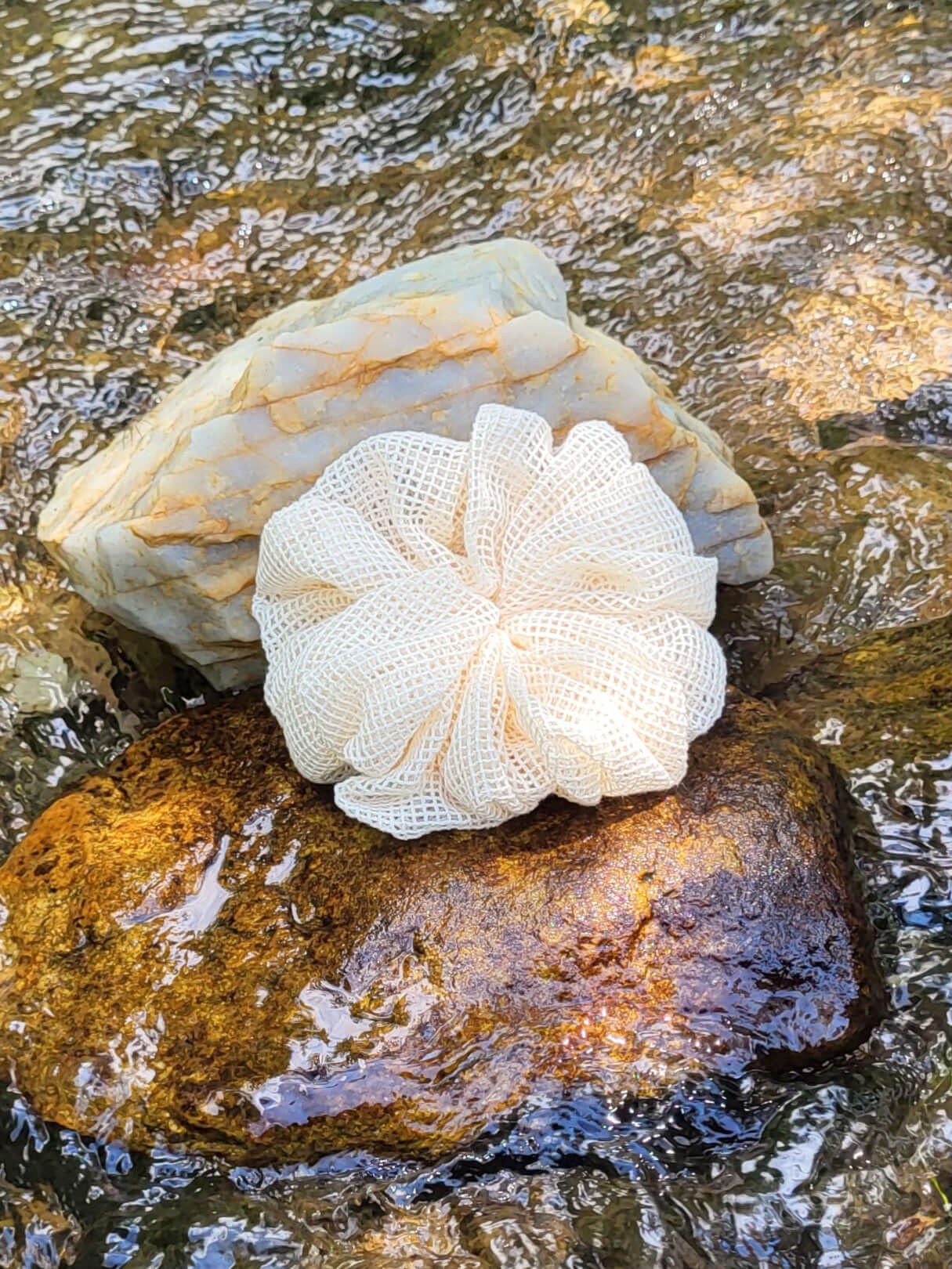 Organic cotton shower pouf in front of a creek