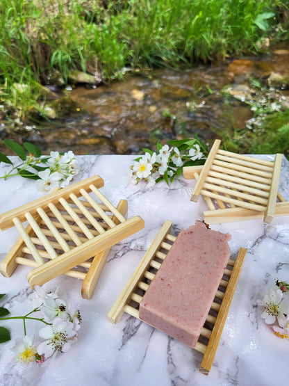 Old fashioned lard rose soap on bamboo soap dish next to a creek