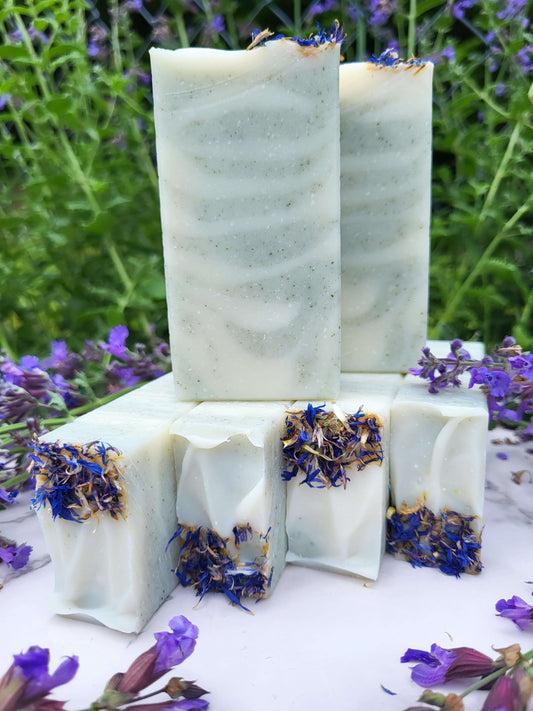 Raccoon lard soap stacked with blue cornflower petals and fresh sage blossoms