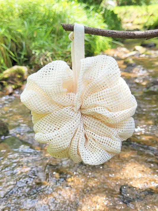 Organic cotton shower pouf in front of a creek